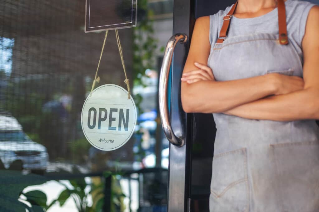 Restaurant, woman standing next to "Open" sign
