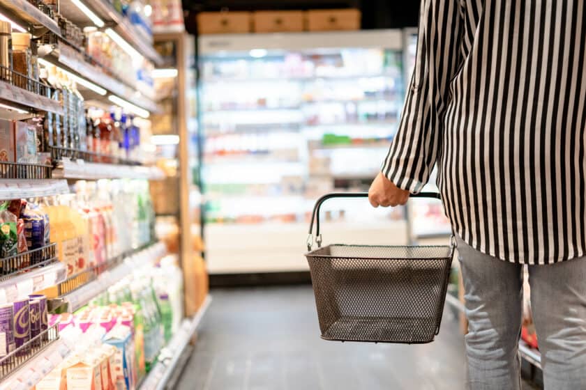 Woman walking with shopping basket in store, consumer goods