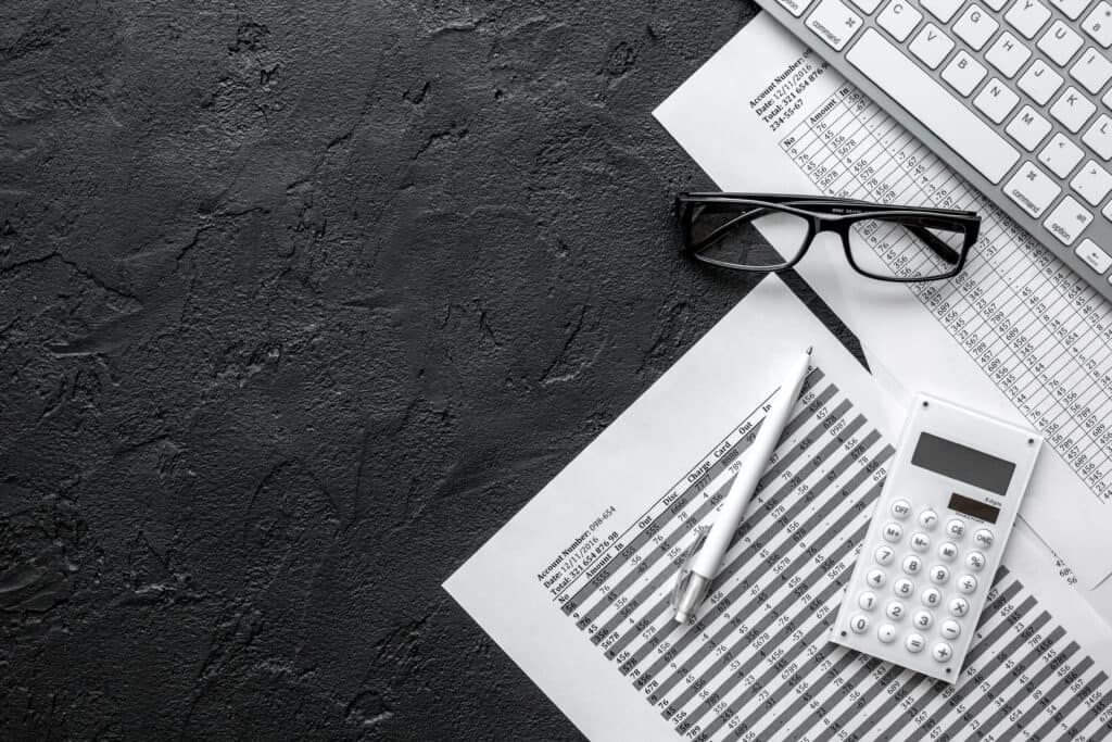 Calculator, eyeglasses, pen on a desk