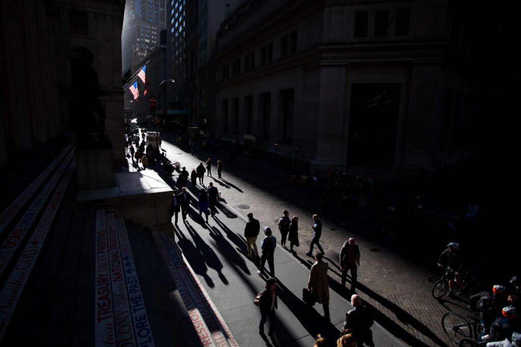 Pedestrians walk along Wall Street near the New York Stock Exchange