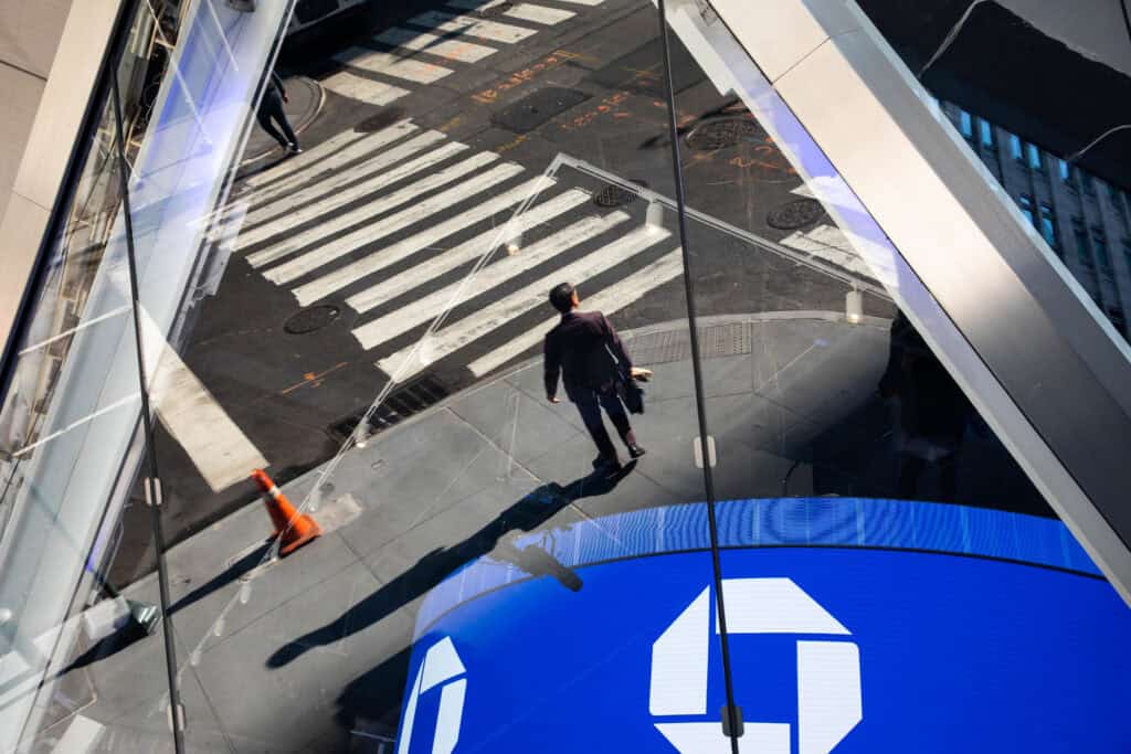 A person is reflected in a window of a JPMorgan bank