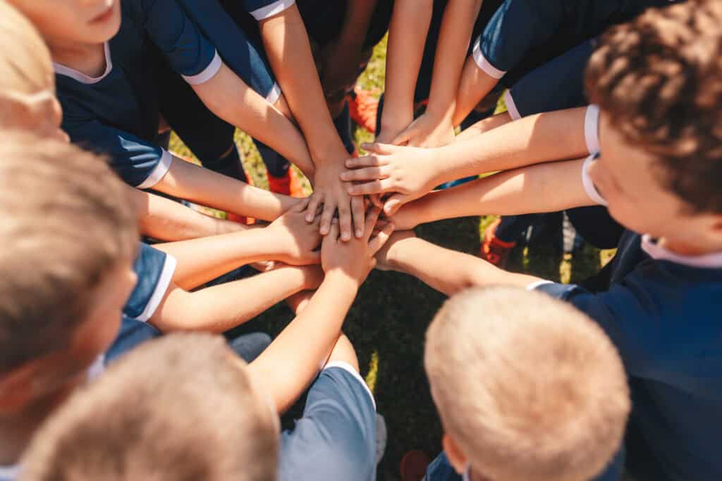 Kids sports team stacking hands at the field