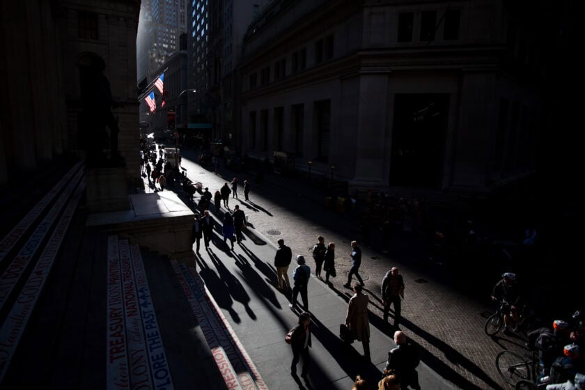 Pedestrians walk along Wall Street