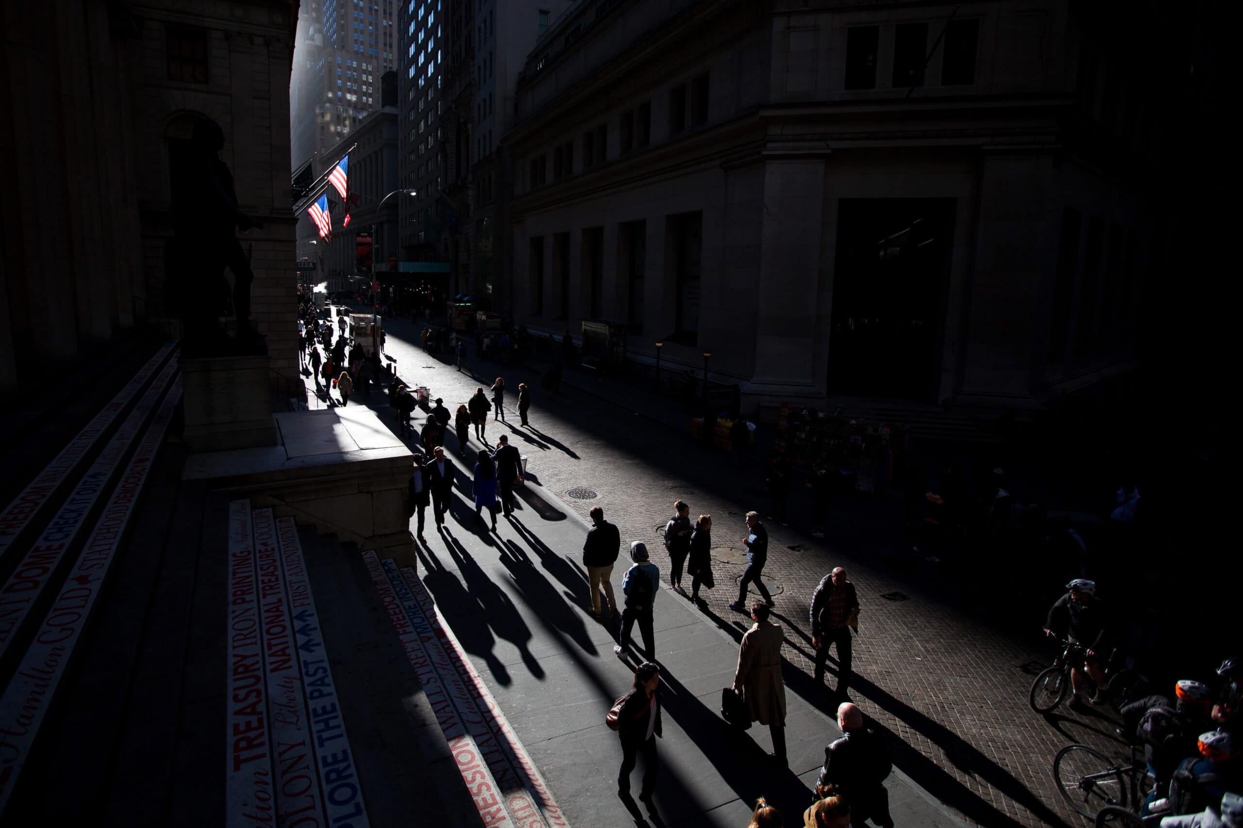 Pedestrians walk along Wall Street