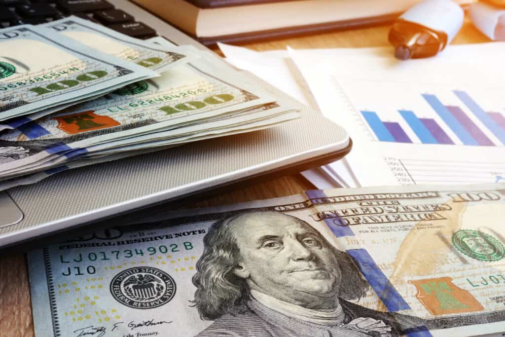 Cash on a laptop and financial documents